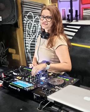 Ga.bih na cabine diante do controlador, parede grafitada ao fundo